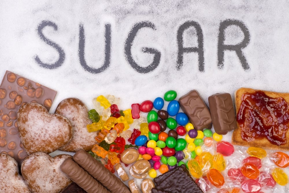 A palavra "sugar" escrita em cima do açúcar. Embaixo, há vários doces
