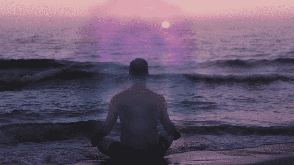 Aura colorida em volta de um homem meditando na praia