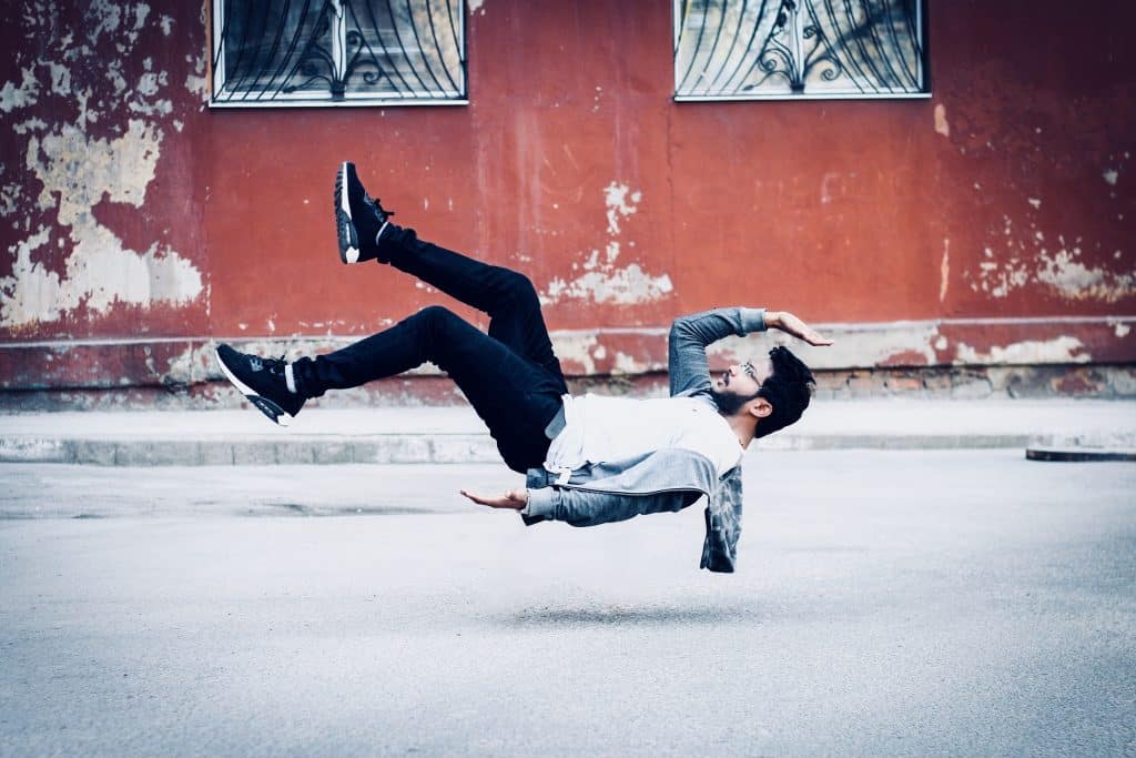 Homem aparentando estar levitando no meio de uma rua.