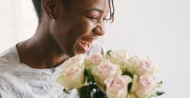 Mulher sorrindo ao lado de umas flores