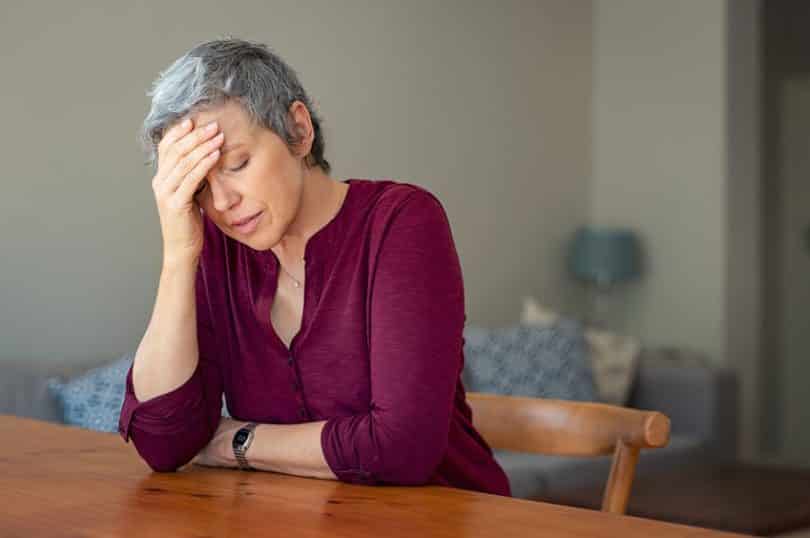 Senhora com mão na cabeça e expressão de estress