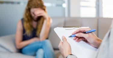 Psicóloga conversando com seu paciente deprimido e fazendo anotações no consultório