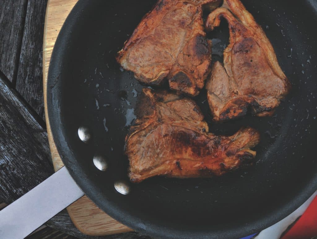 Pedaços de carne carbonizados em uma frigideira.