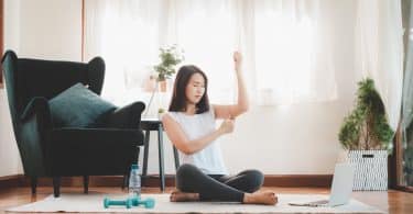 Mulher asiática sentada apertando braço.