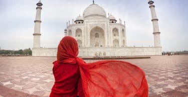 Mulher sentada de costas com Taj Mahal ao fundo