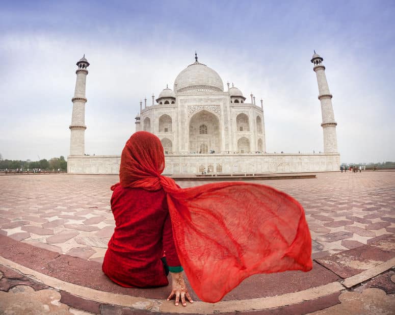 Mulher sentada de costas com Taj Mahal ao fundo