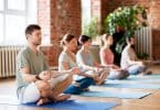 Grupo de pessoas meditando em uma sala, lado a lado.