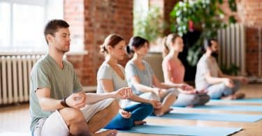 Grupo de pessoas meditando em uma sala, lado a lado.