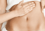 Mulher deitada recebendo massagem no abdomen