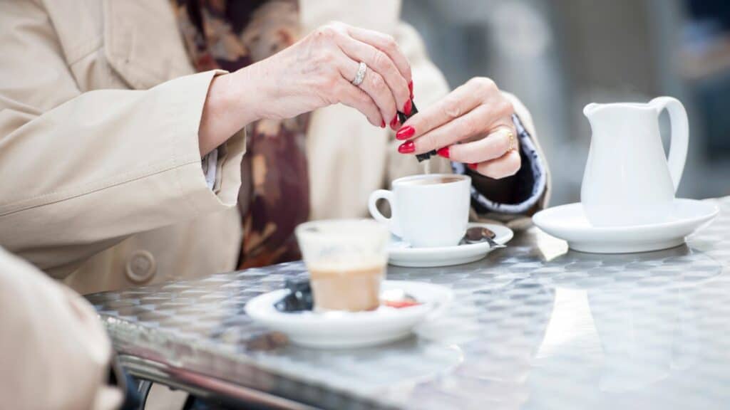 Mulher colocando adoçante na xícara de café