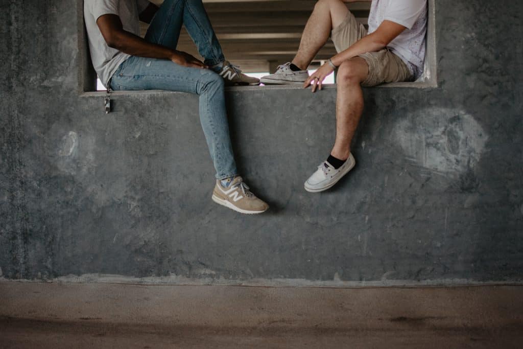 Duas pessoas sentadas em um muro de frente para o outro