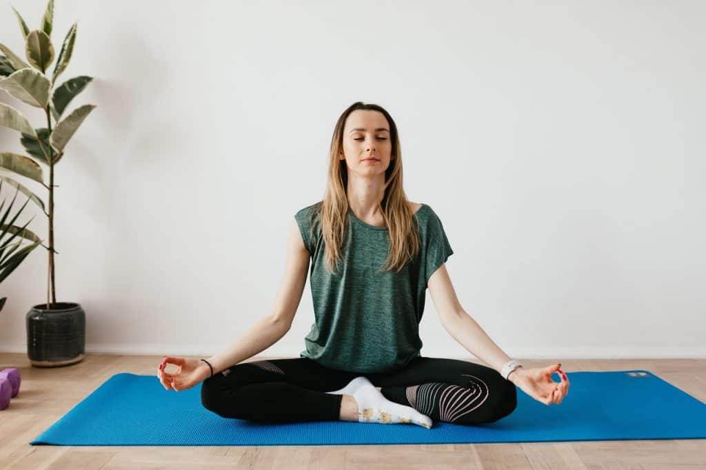 Mulher sentada no chão, meditando.