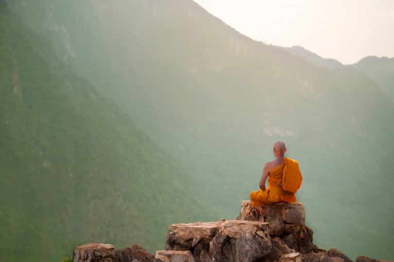 Monge budista meditando em uma montanha.