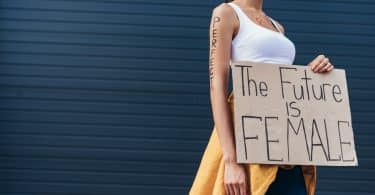 Mulher segurando cartaz escrito em inglês "o futuro é feminino"