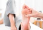 Fisioterapeuta fazendo reflexologia podal nos pés de uma paciente,