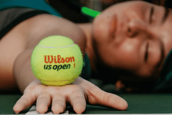 Mulher deitada no chão segurando bola de tênis
