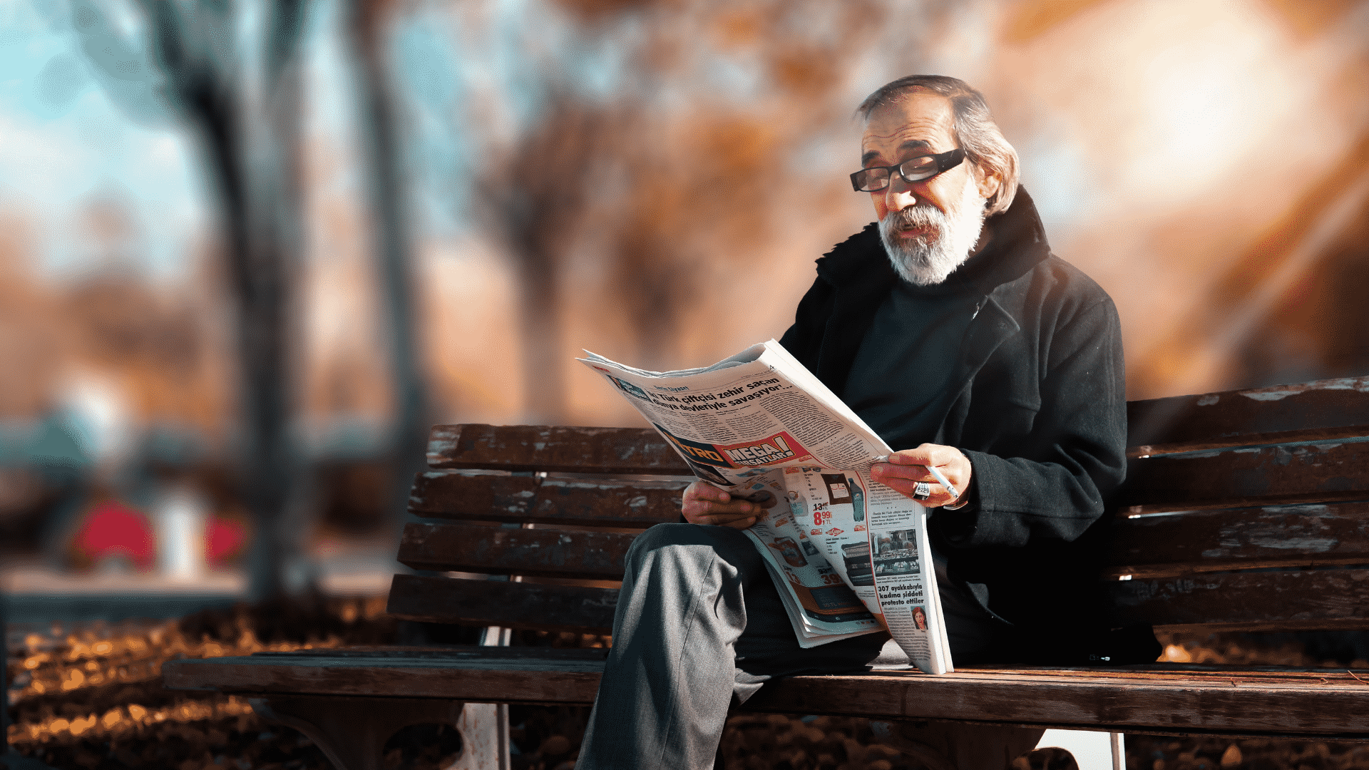 Idoso lendo jornal sentado no banco da praça
