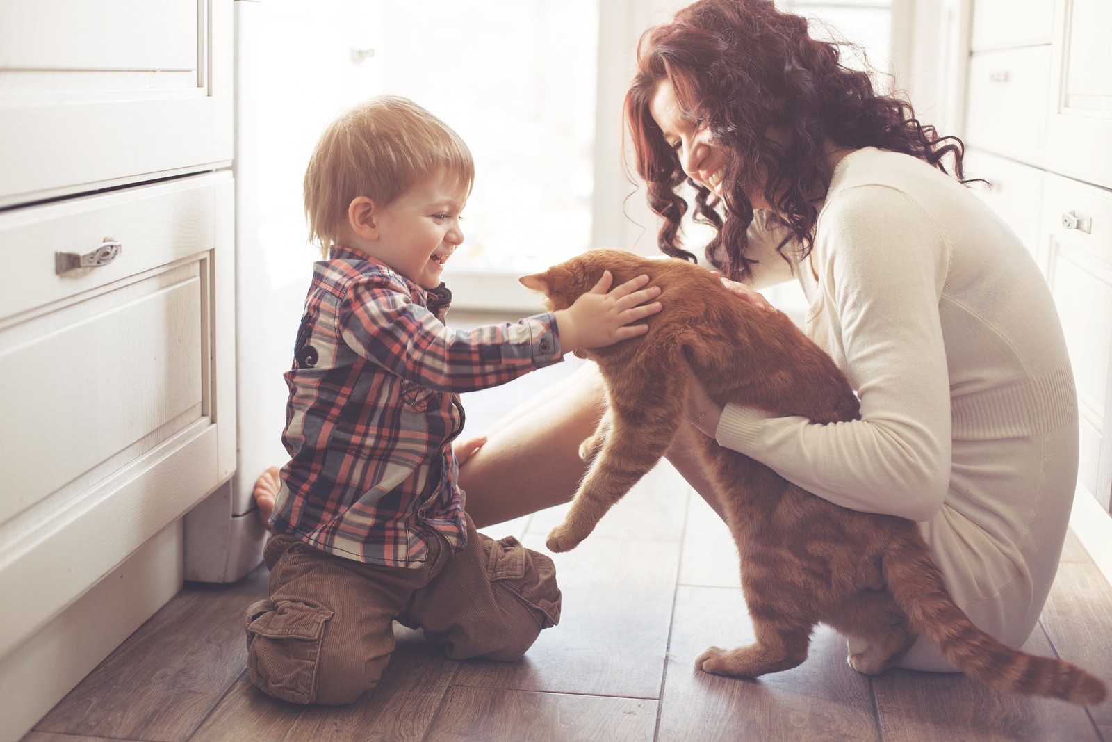 Mother with her baby playing with pet on the floor at the kitche