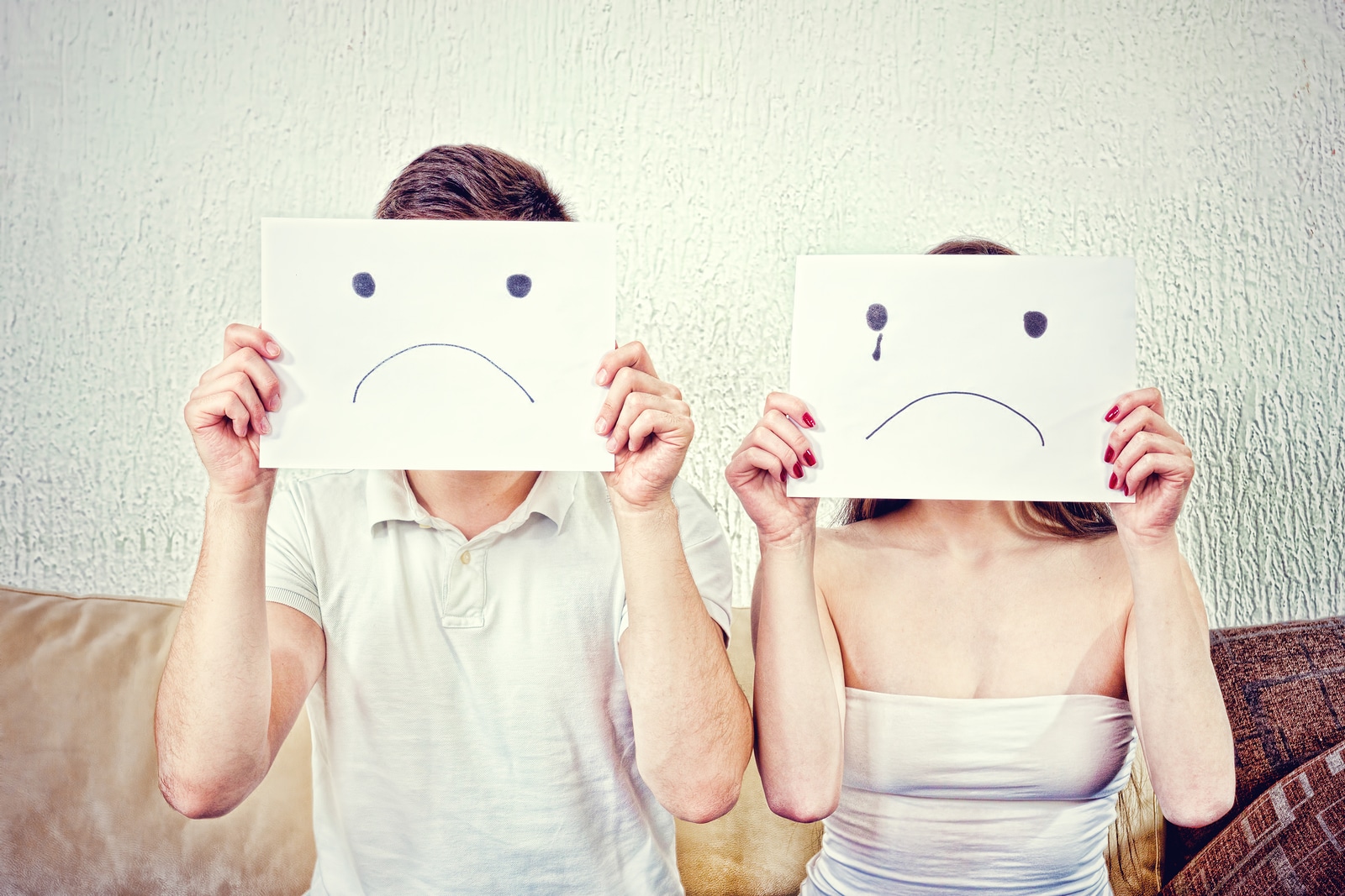 Unhappy Young Couple In Despair Sitting On Couch