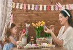 Uma mãe e sua filha usando orelhas de coelho pintando ovos de Páscoa.