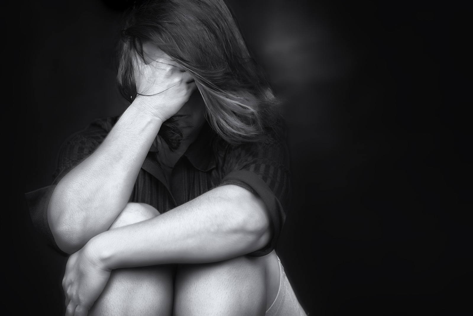 Black and white image of a young woman crying and covering her f