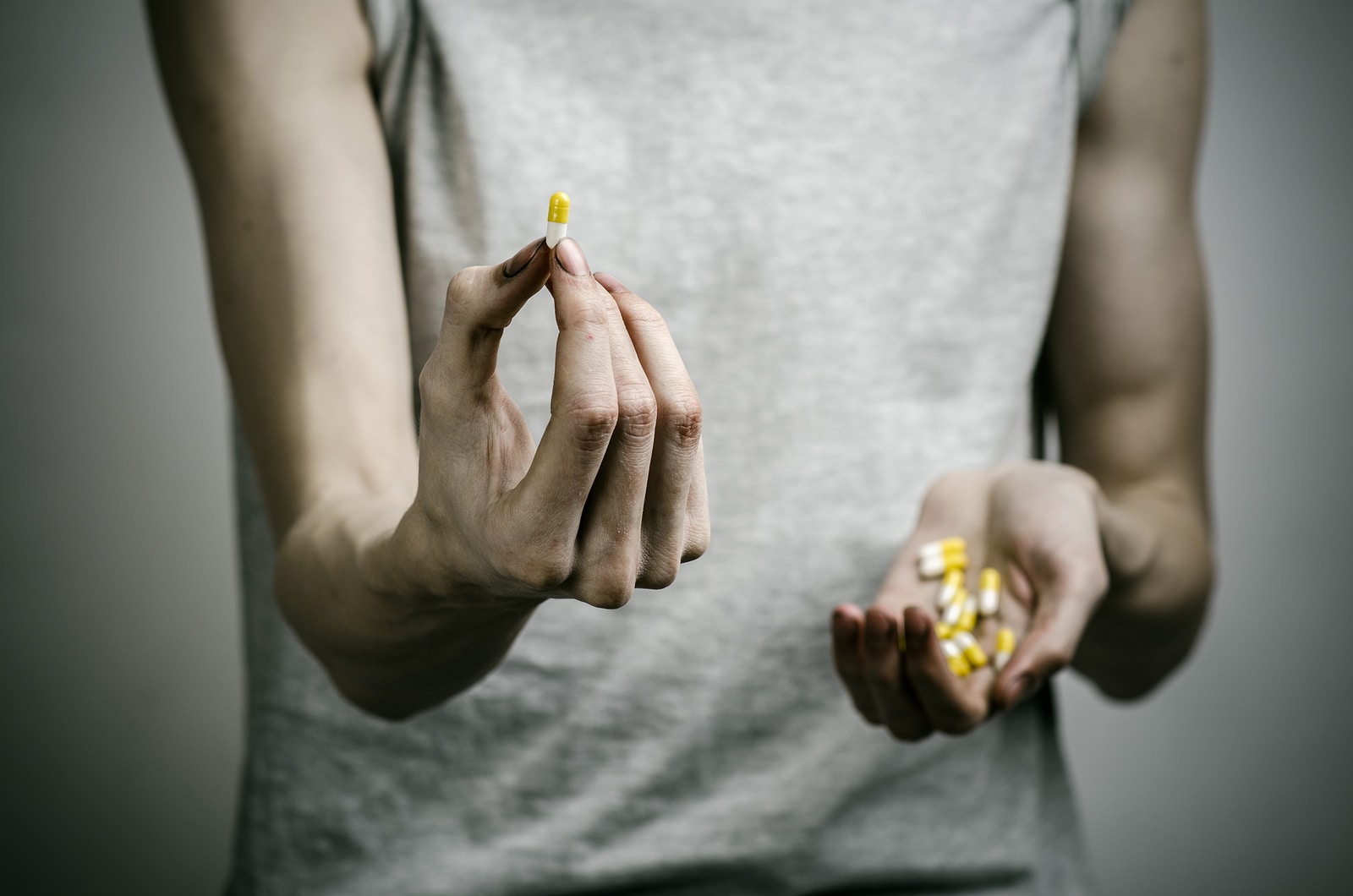 he fight against drugs and drug addiction topic: addict holding a narcotic pills on a dark background in studio