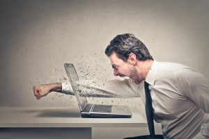 furious businessman throws a punch into the computer