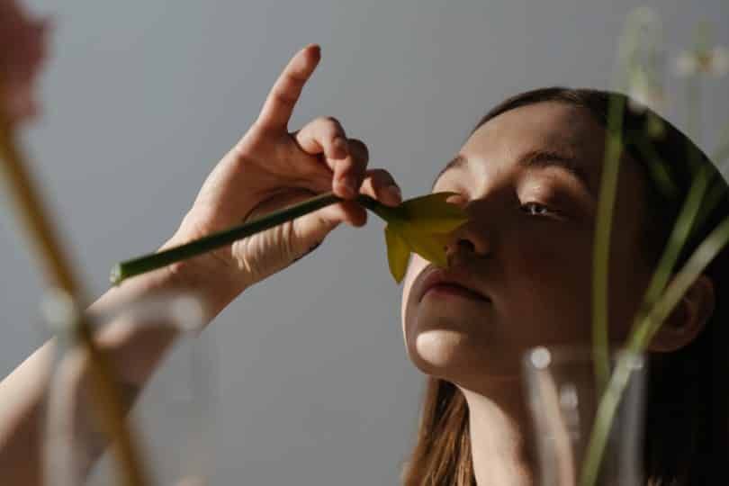 Mulher cheirando flor olhando para frente