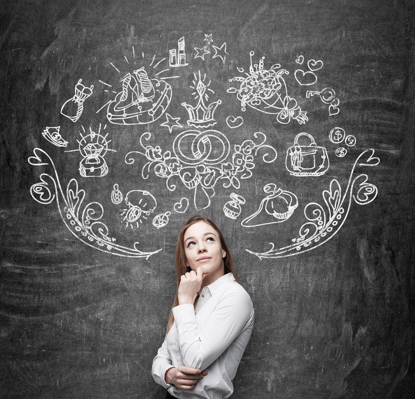 Young woman is dreaming about sopping. Shopping icons are drawn on the black chalkboard.