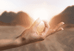 Mão de pessoa meditando durante por do sol