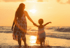 Mãe e filha de mãos dadas andando na praia