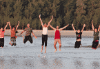 Diversas pessoas em uma praia pulando para a foto
