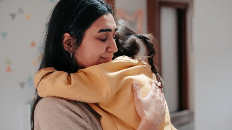 Mãe abraçando sua filha com expressão de emoção