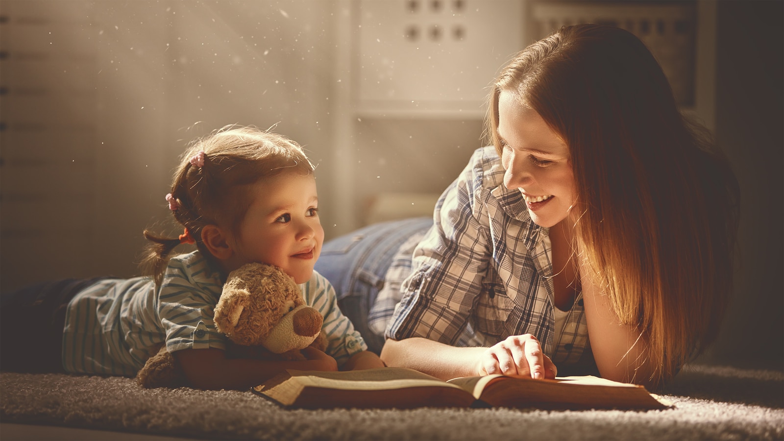 happy family mother and daughter read a book in the evening at home