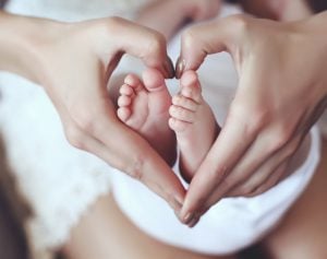 tender interior photo of cute baby feets in mom hands holding them in heart shape