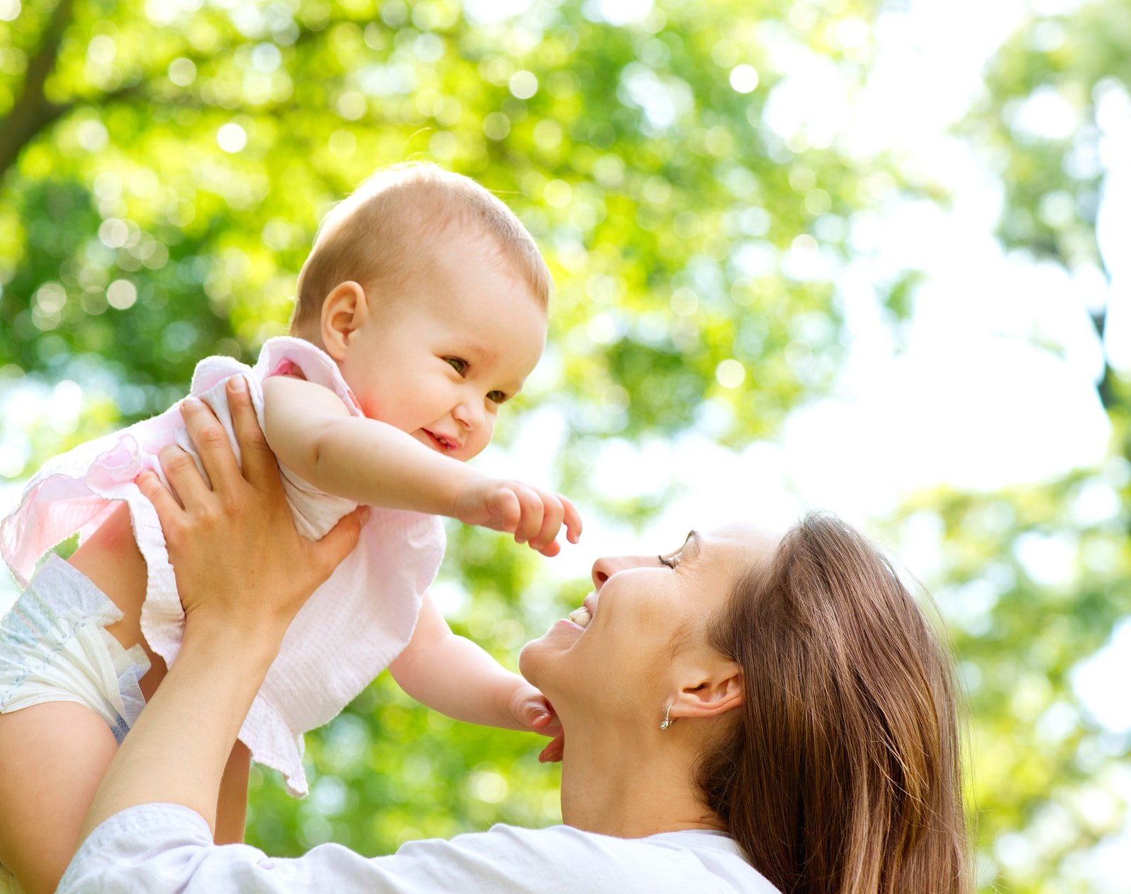 Beautiful Mother And Baby outdoors. Nature. Beauty Mum and her Child playing in Park together. Outdoor Portrait of happy family. Joy. Mom and Baby