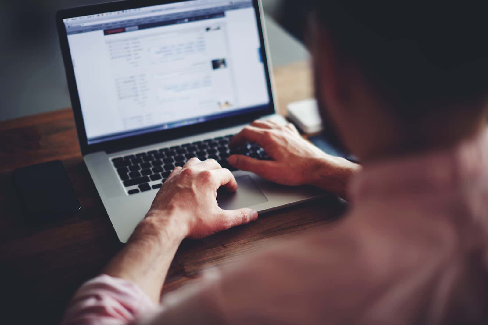 Young man working on his laptop in a coffee shop, rear view of business man hands busy using laptop at office desk ** Note: Shallow depth of field