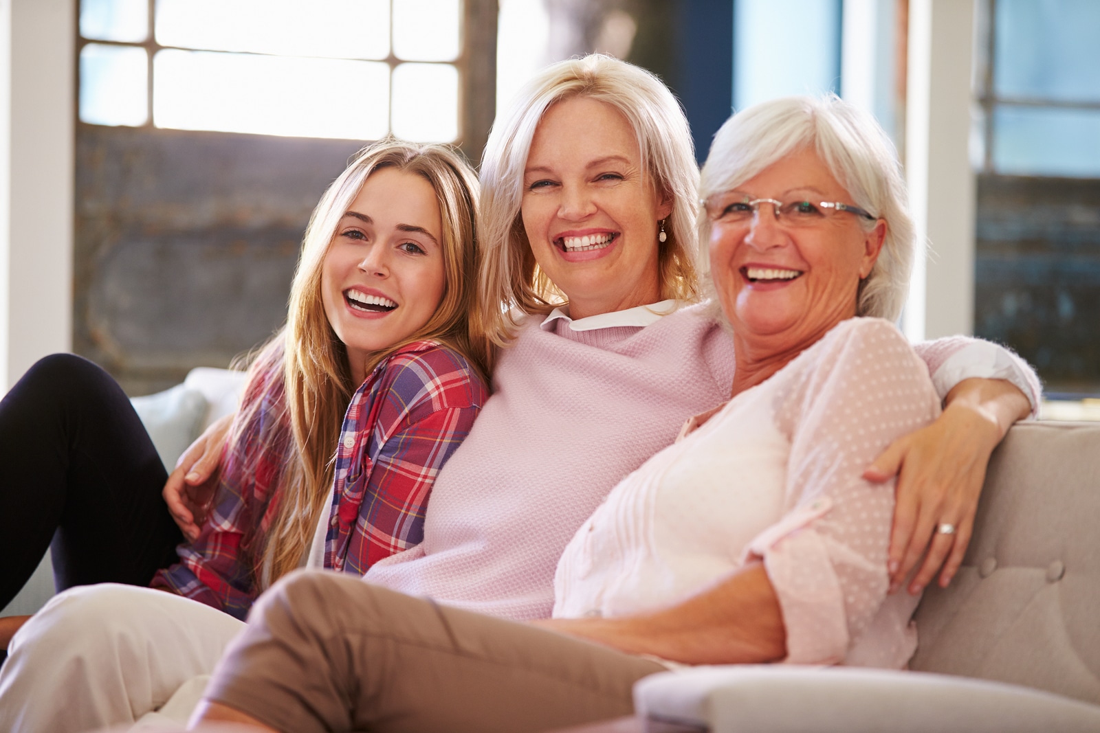 Grandmother With Mother And Adult Daughter Relaxing On Sofa