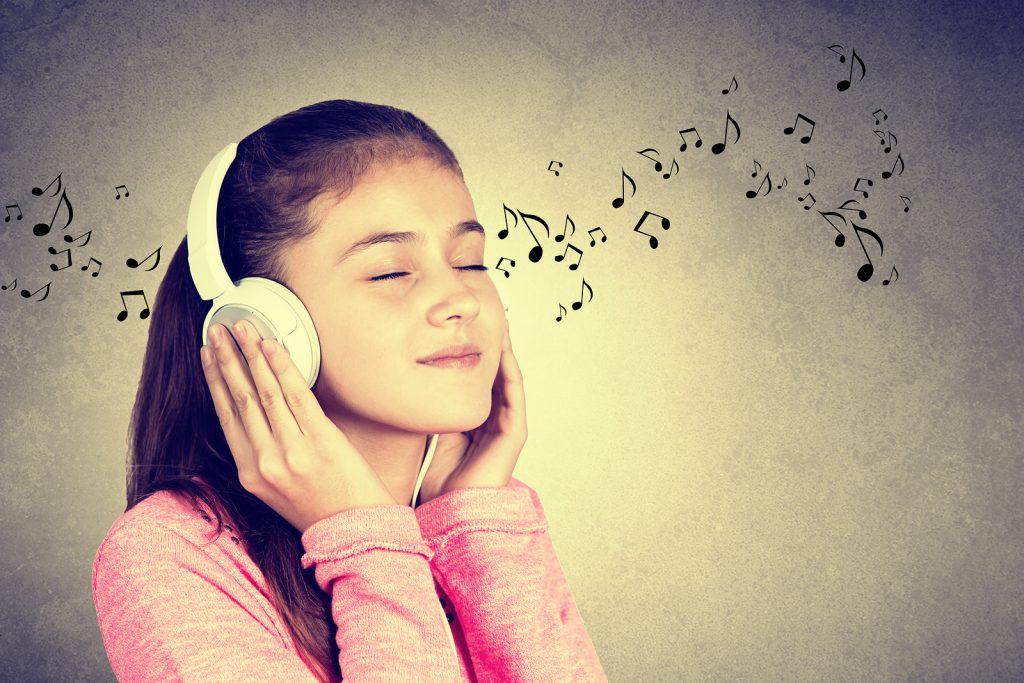 Little girl enjoying music in headphones at home relaxing. Relaxed little girl listening to music with earphones with eyes closed looking serene and happy.