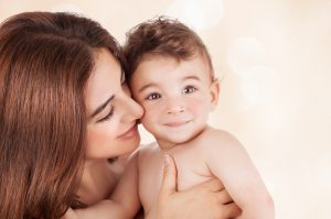 Mother and baby boy closeup portrait, happy faces over beige bac