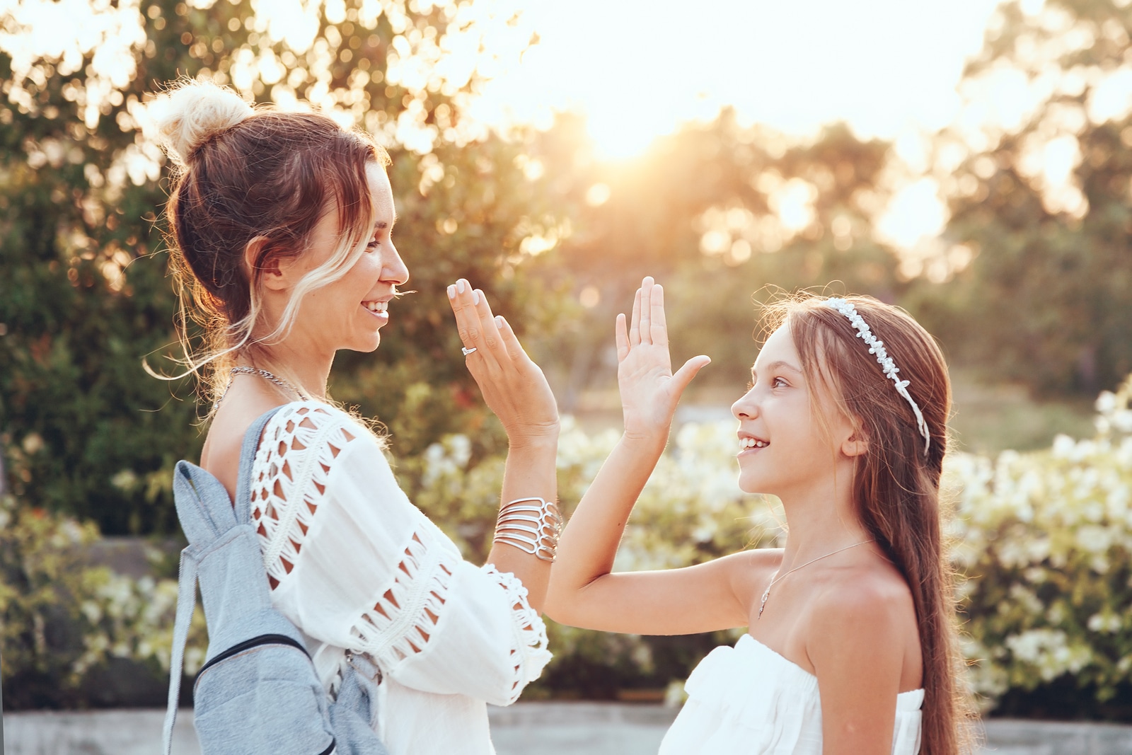 Tween daughter holding hands her mom in summer sunlight