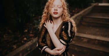 Mulher albina com a mão sobre o peito.