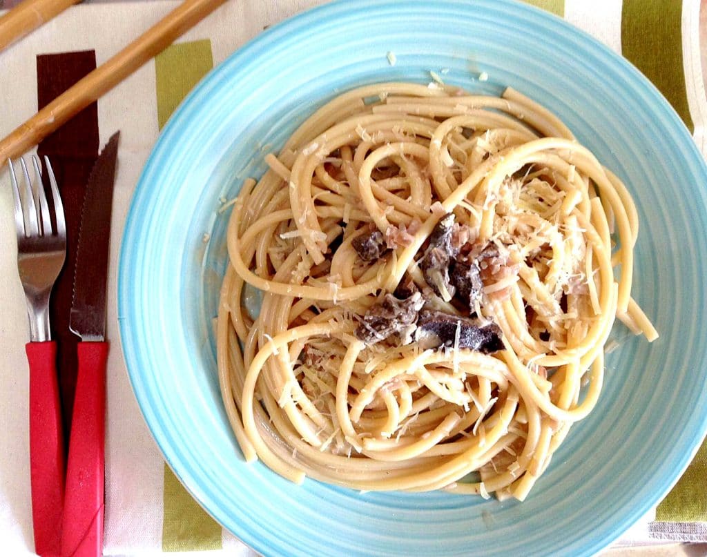 Prato azul com porção generosa de espaguete, com funghi no centro.