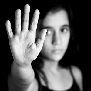 Black and white image of a girl with her hand extended signaling to stop useful to campaign against violence, gender or sexual discrimination (image focused on her hands)