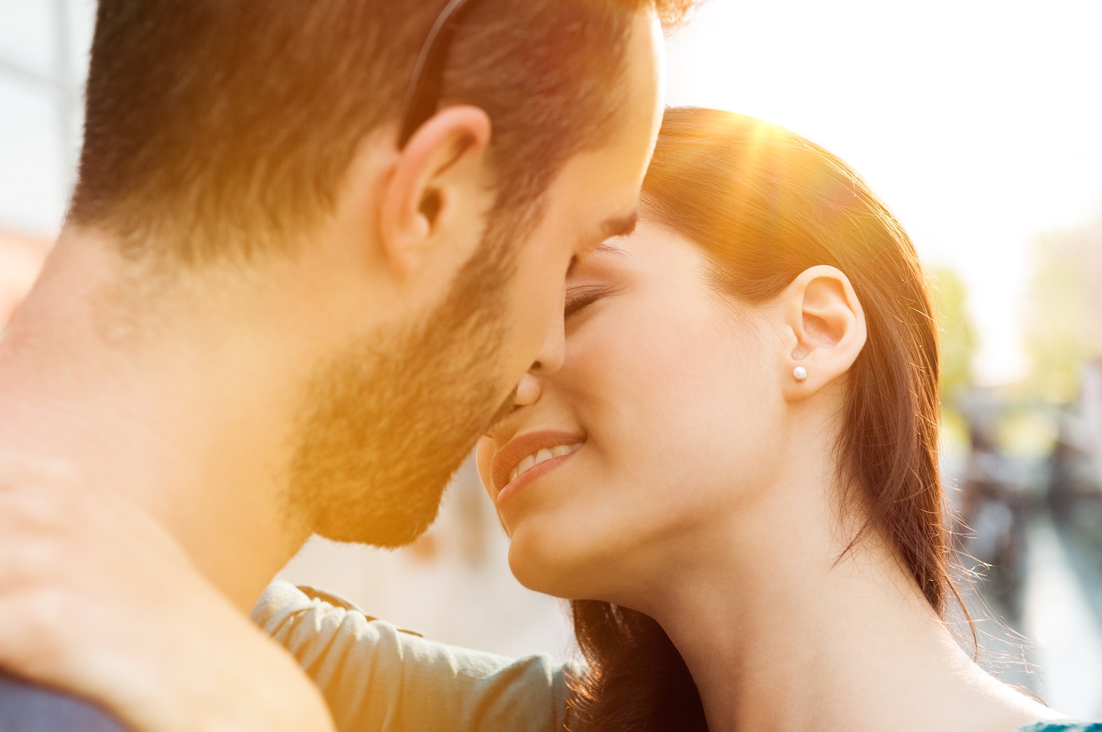 Closeup shot of young couple kissing outdoor. Close up of loving couple embracing and kissing. Shallow depth of field with focus on young couple kissing.