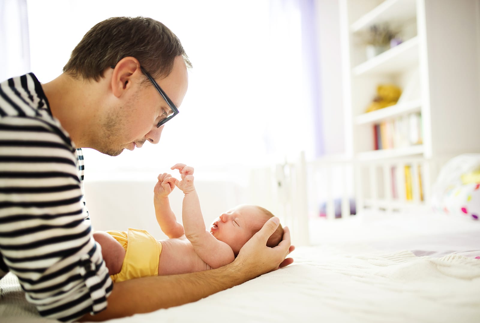 Happy young father enjoying special moments with his newborn baby daughter at home