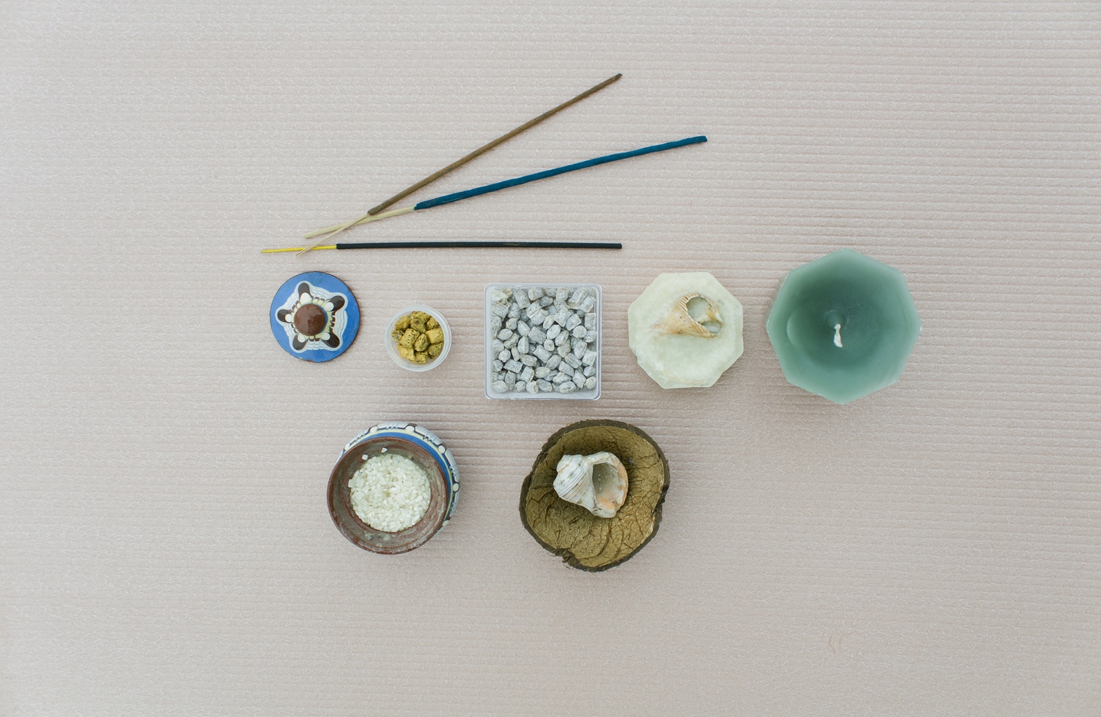 The composition of the components of a meditation on light beige background. Church and Indian incense and incense candles and shells a pot of rice as a stand rod.