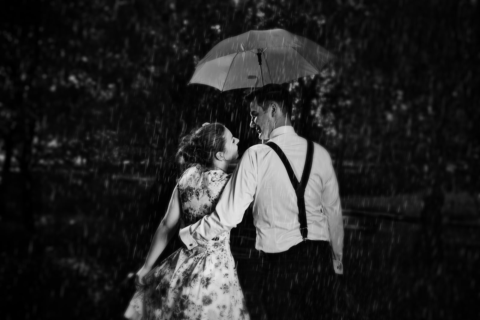 Young romantic couple in love flirting in rain, man holding umbr