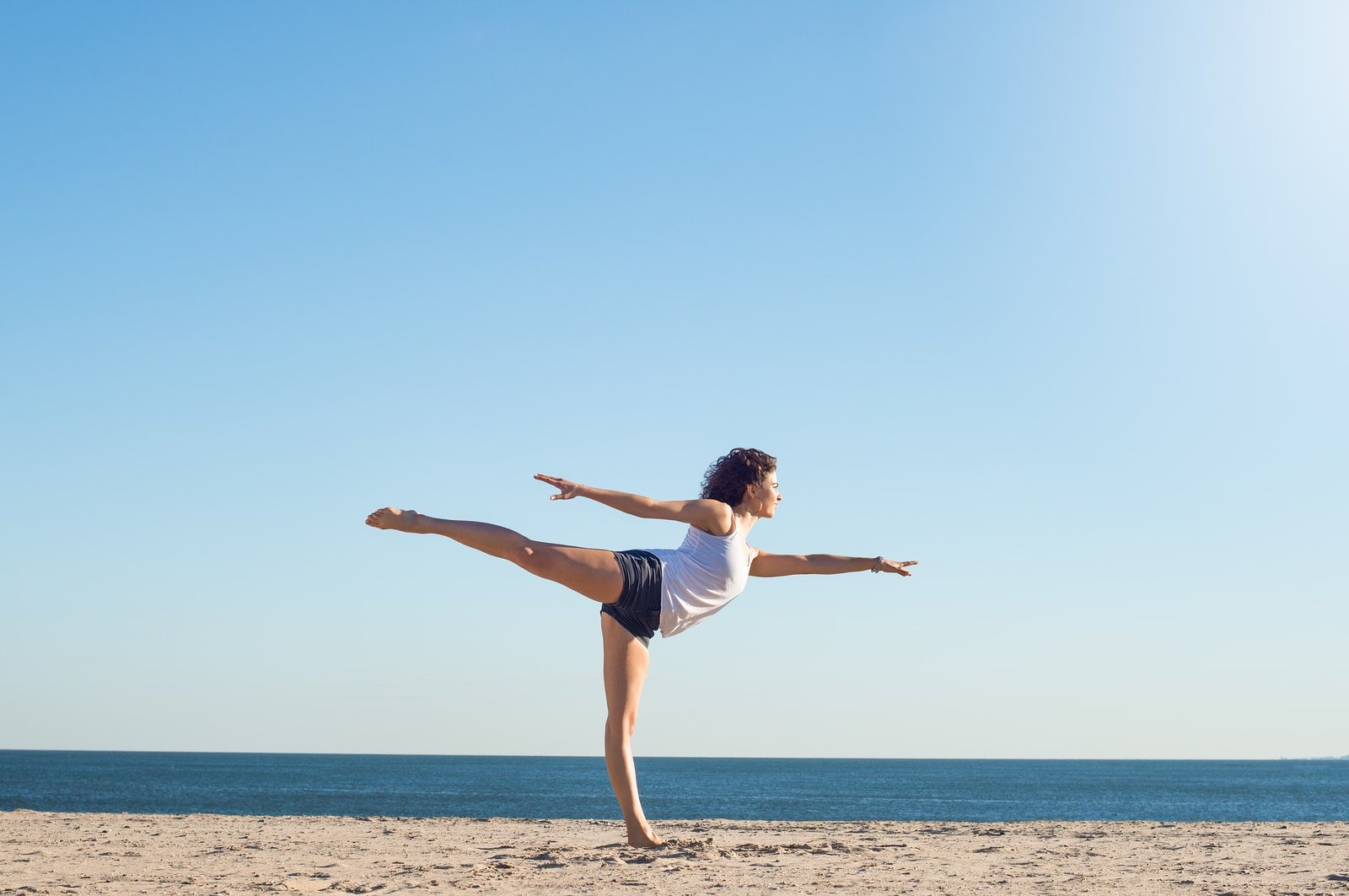 Young woman performing yoga on the beach during a beautiful morn