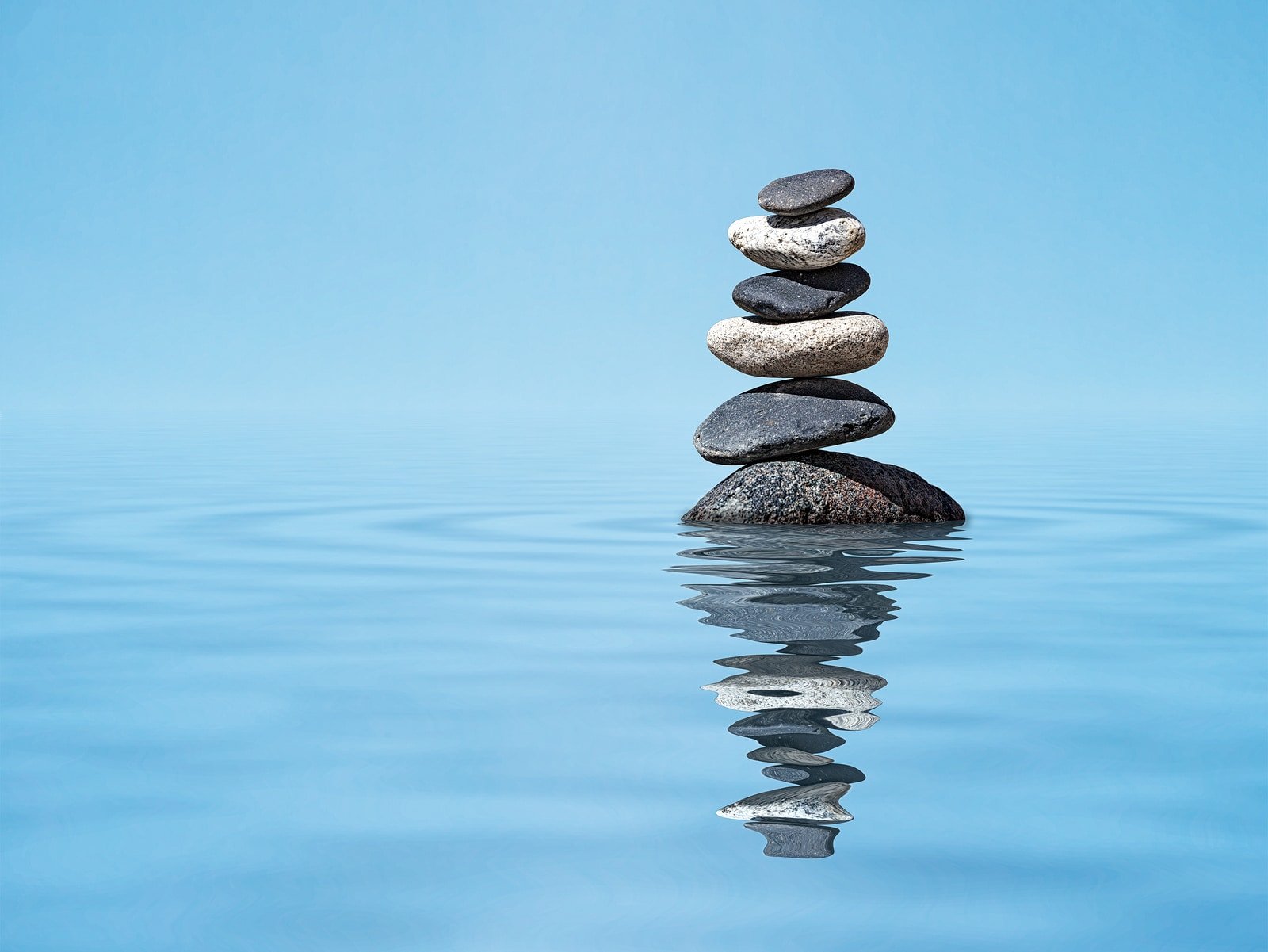 Zen meditation relaxation peacefulness peace of mind concept background - balanced stones stack in water with reflection
